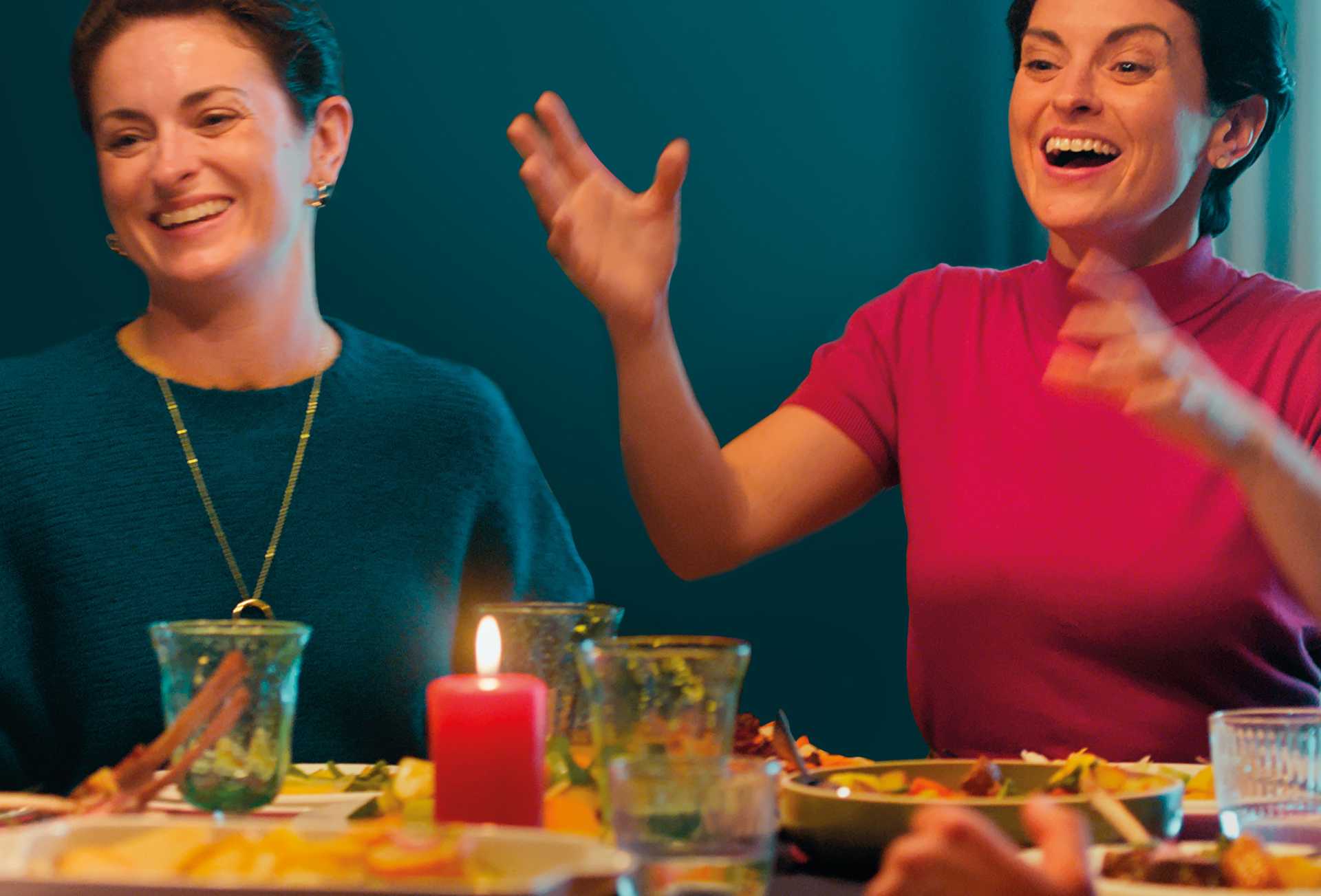 Two women sitting at a dinner table experience relief from heartburn and indigestion.